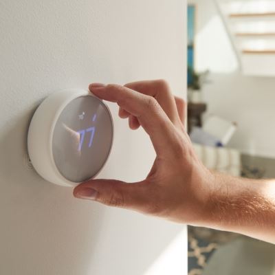 Close up of a person's hand adjusting a wall thermostat